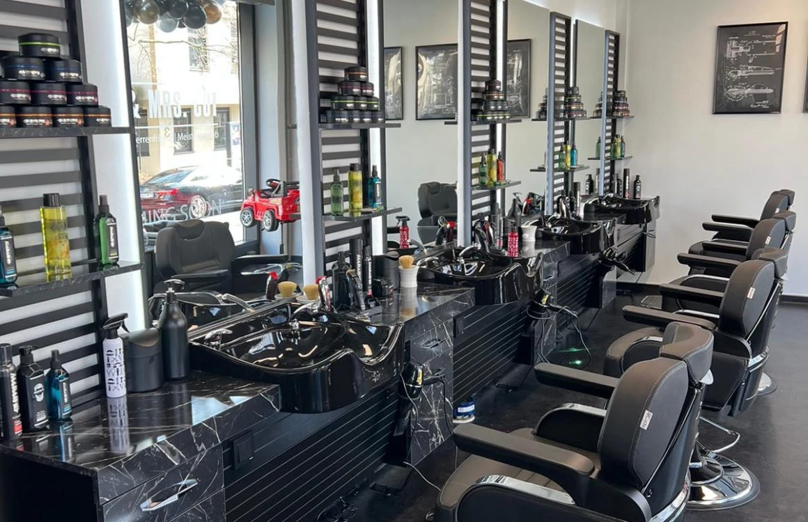 Originalaufnahme des Salons MR. & MRS. CUT in Hofheim: schwarze Stylingstühle, große Spiegel und edle Marmordetails